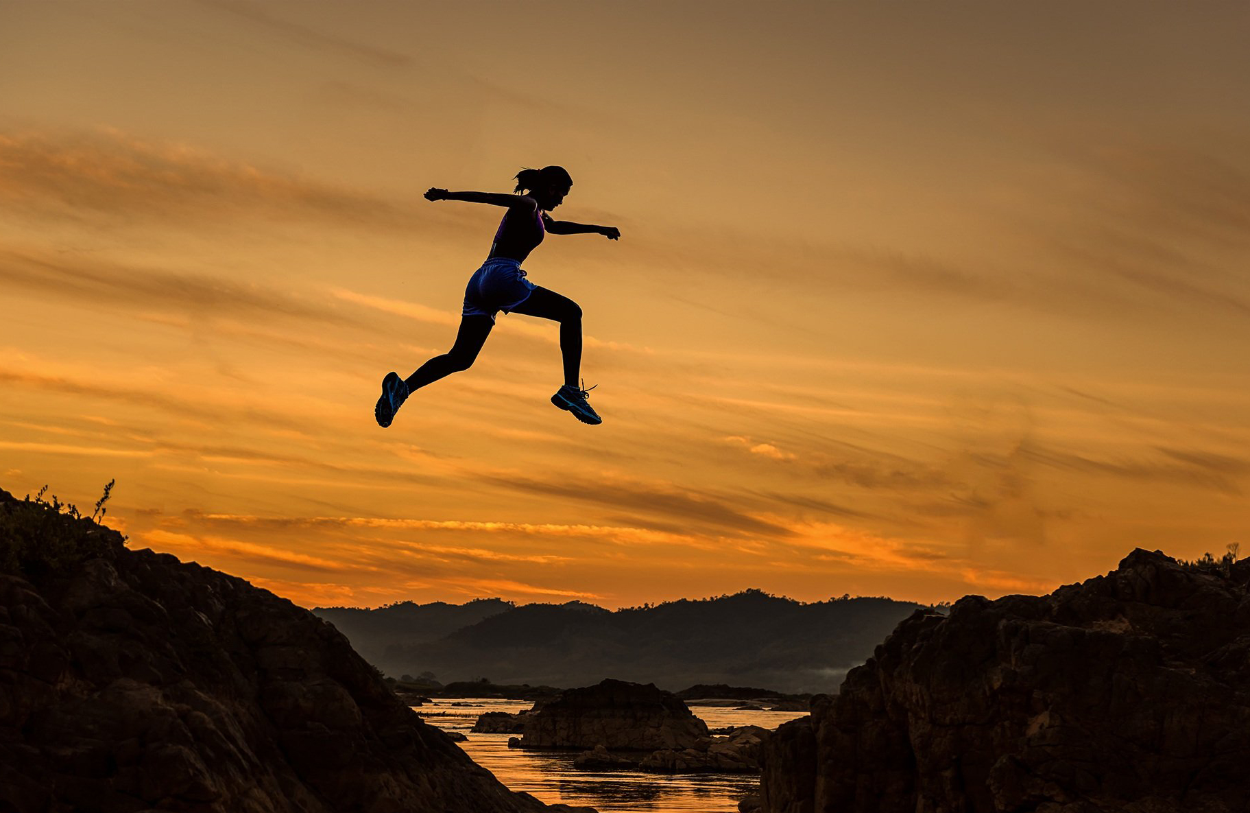 lady jumping over hills at sunset